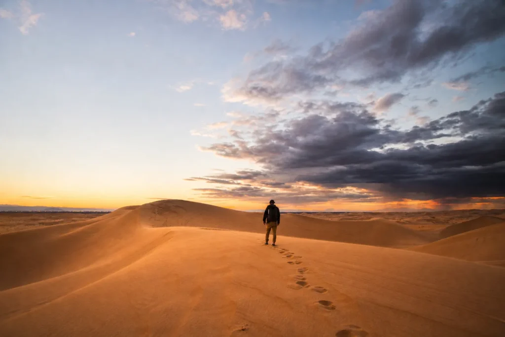 Persona caminando por las dunas al atardecer
